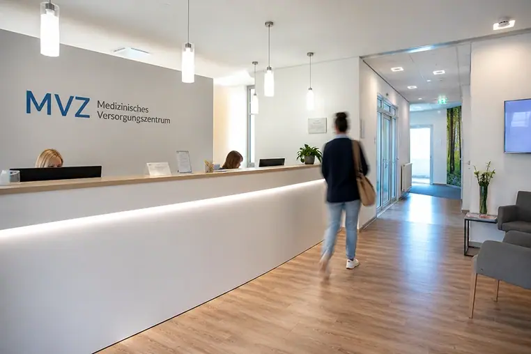 Empfangsbereich eines Medizinischen Versorgungszentrums (MVZ) mit Patienten und medizinischem Personal.