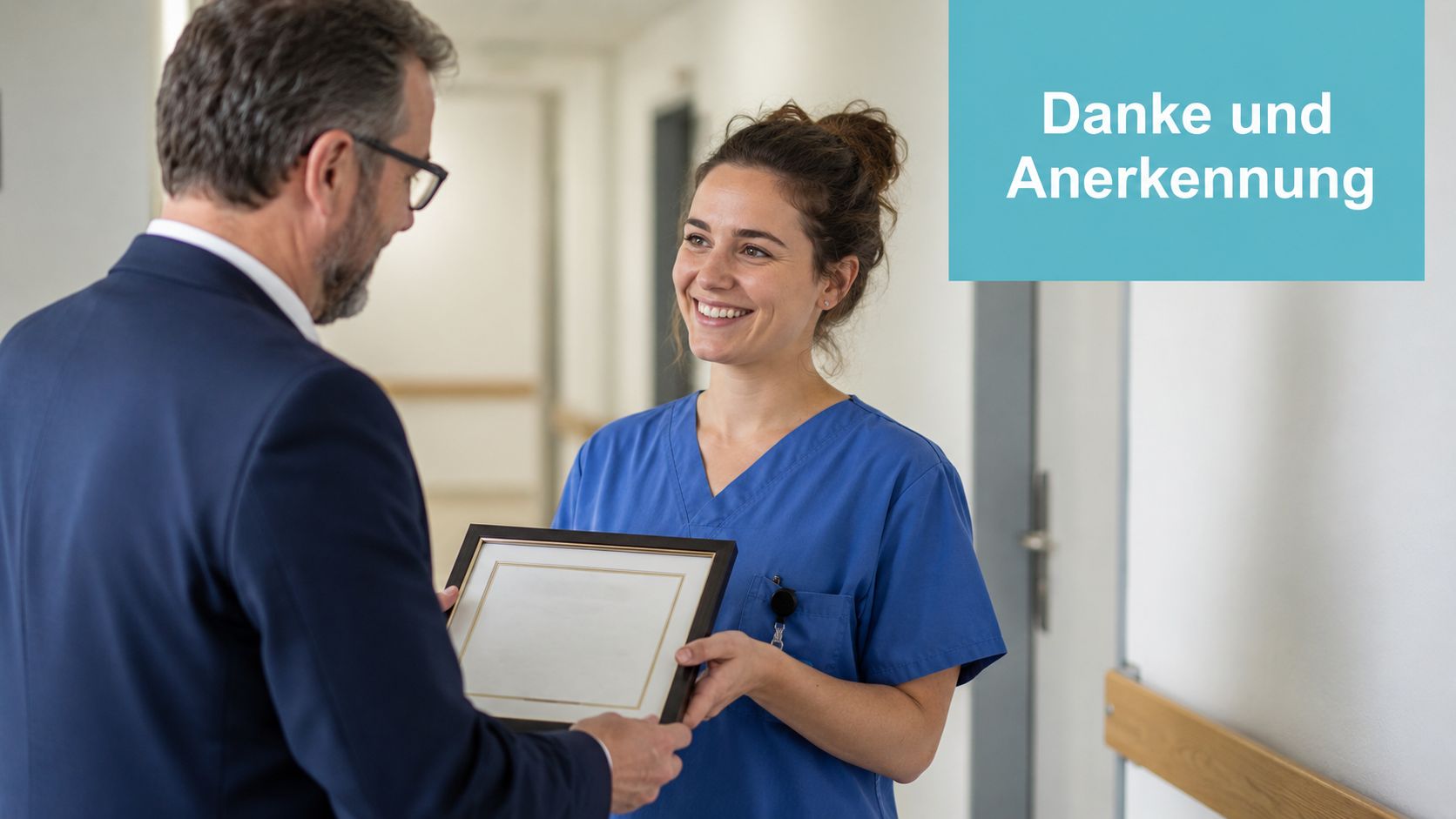 Ein Mann im Anzug überreicht einer lächelnden Krankenschwester in blauer Arbeitskleidung eine Ehrenurkunde im Krankenhausflur.