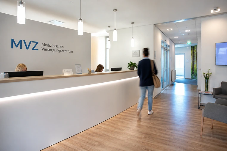 Empfangsbereich eines Medizinischen Versorgungszentrums (MVZ) mit Patienten und medizinischem Personal.