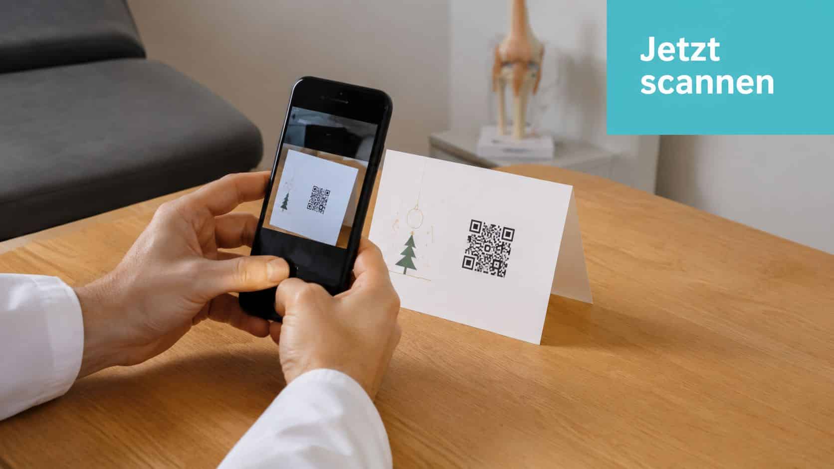 Ein Arzt hält ein Smartphone, um den QR-Code auf einer Weihnachtskarte für Patienten zu scannen.