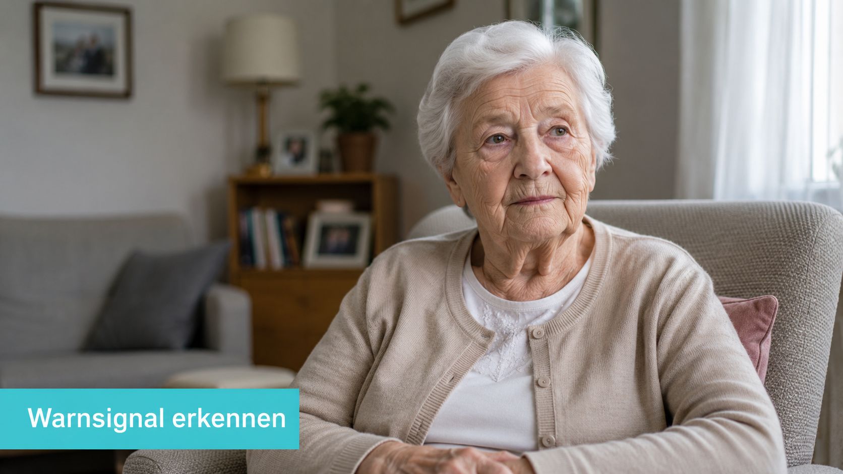 Eine ältere Frau mit weißem Haar sitzt nachdenklich in einem Sessel und blickt in die Ferne.
