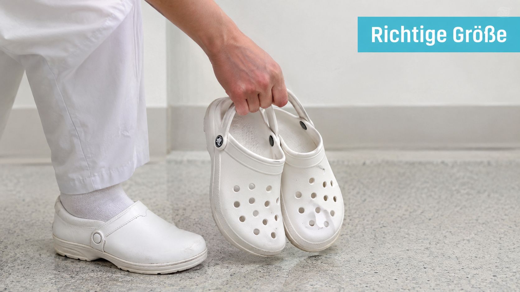 Eine Person trägt medizinische Arbeitsschuhe und hält zwei weiße Crocs in der Hand für den Größenvergleich.